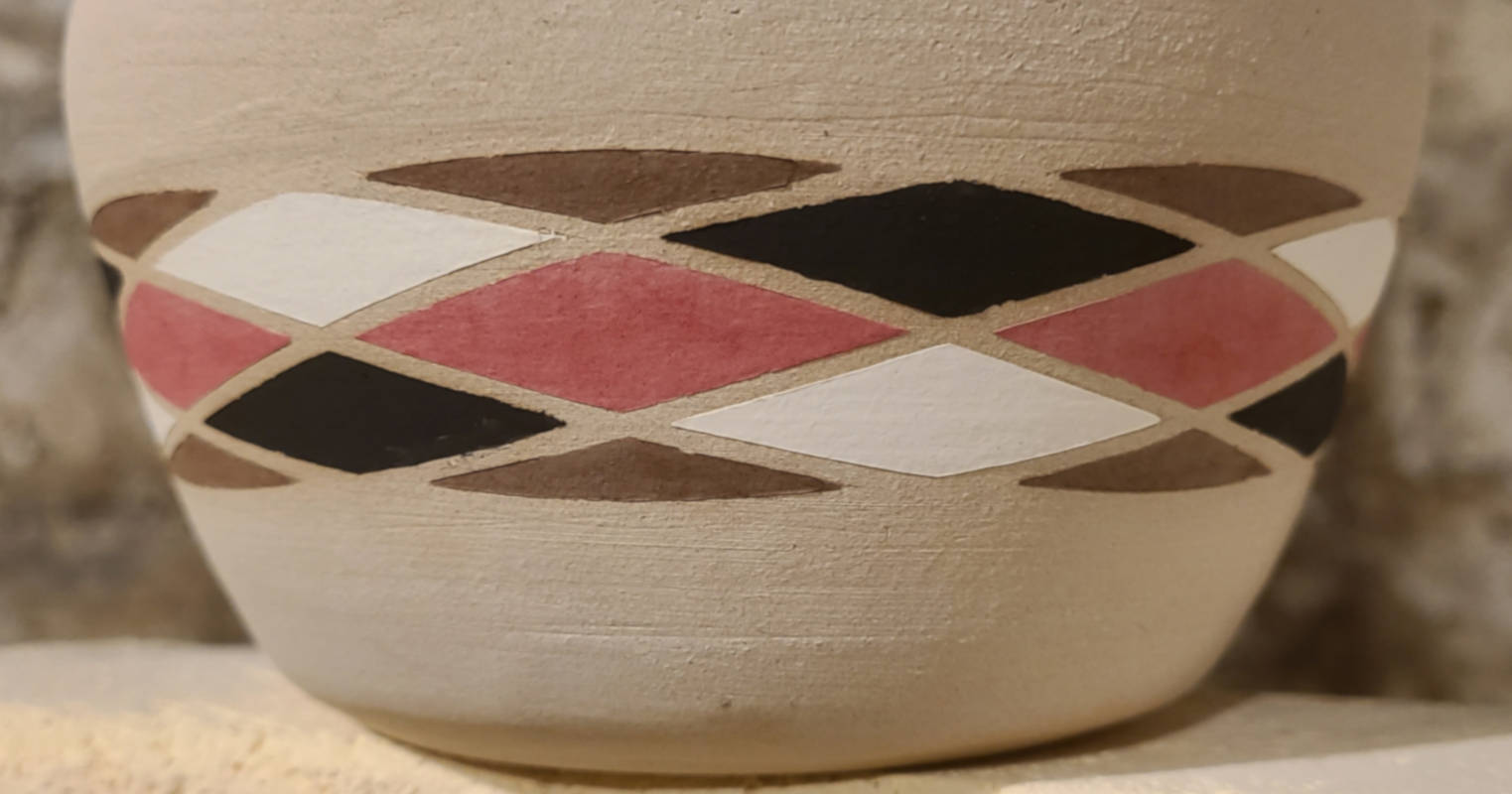 Completed bisqueware vase with artwork around the conical circumference